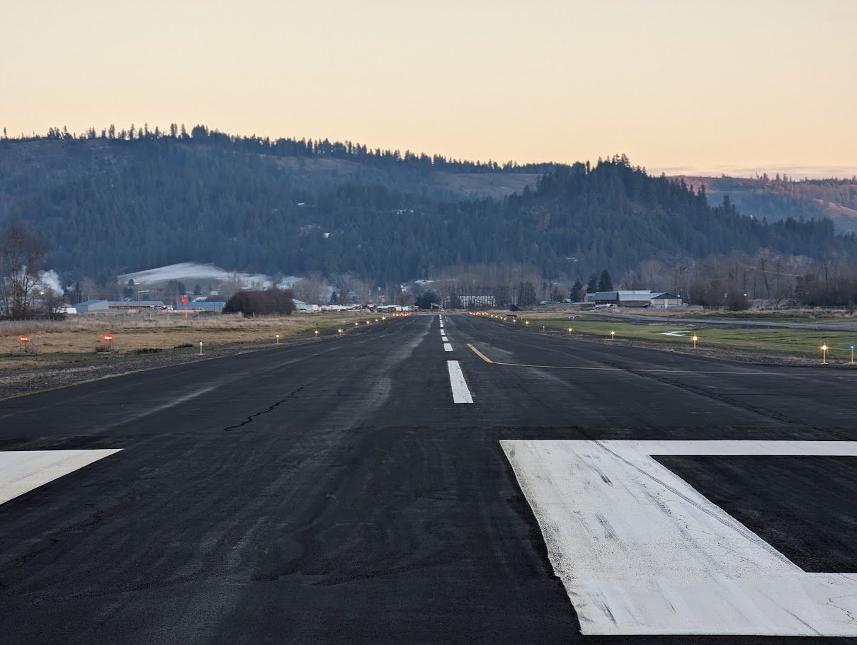 Looking down the runway at Jack A. Buell Airport toward the hills above St. Maries at dawn, runway edge lights on